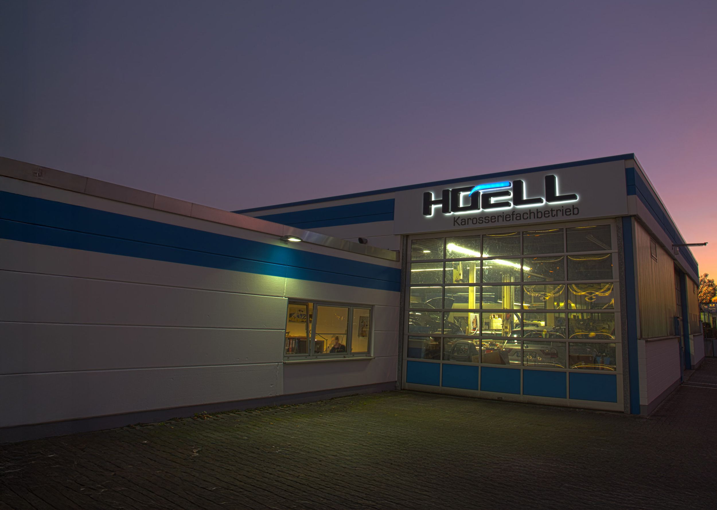 Eine Frontansicht der Werkstatt der Hoell GmbH & Co. KG im Abendlicht.